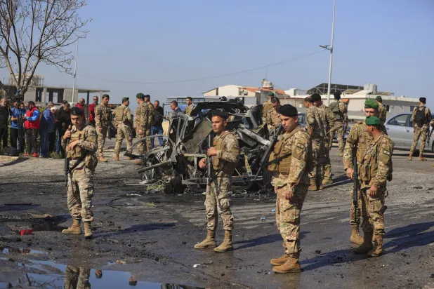 عناصر من الجيش اللبناني يقفون قرب سيارة استهدفتها مسيرة إسرائيلية في بلدة الغازية بجنوب لبنان الجمعة (أ.ب)