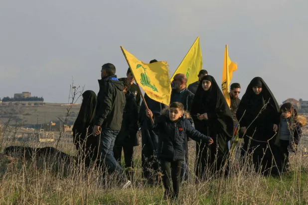 لبنانيون يتحدرون من بلدة ميس الجبل يحملون أعلام «حزب الله» بعدما منعهم الجيش الإسرائيلي من العودة لبلدتهم بجنوب لبنان في فبراير الماضي (أ.ف.ب)