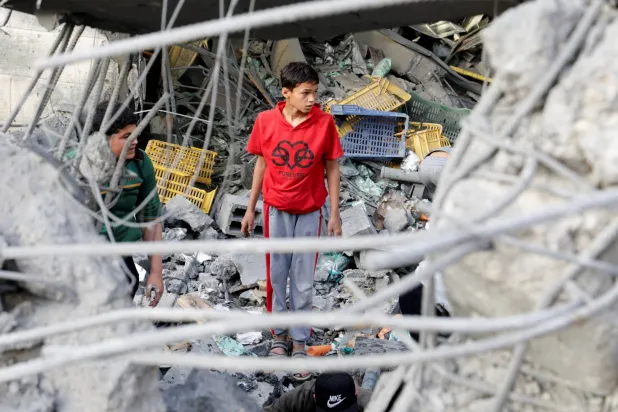 فلسطينيون يتفقّدون موقع غارة إسرائيلية على منزل في خان يونس جنوب قطاع غزة اليوم (رويترز)