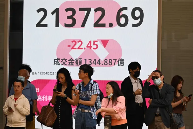 مشاة يسيرون أمام شاشة تظهر حركة الأسهم في هونغ كونغ (أ.ف.ب)