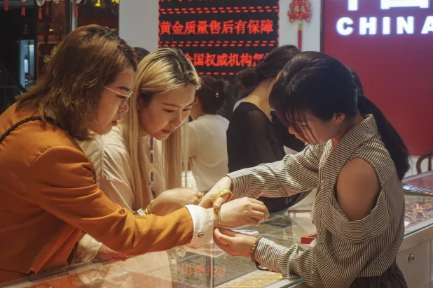 سيدة تجرب أسورة ذهبية في أحد المتاجر بمدينة هوانغزو شرق الصين (أ.ف.ب)