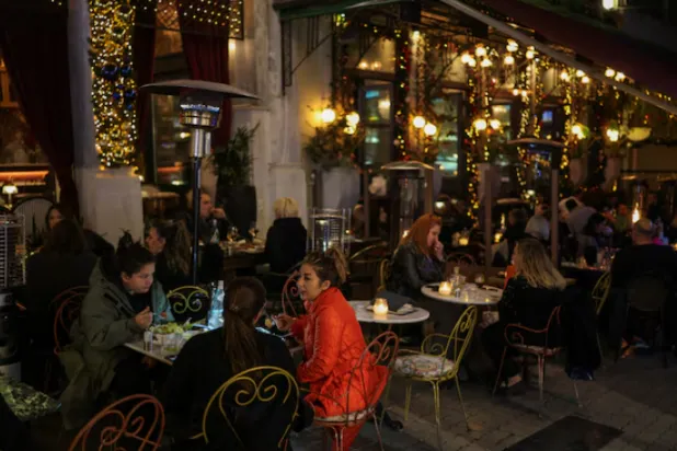 يتناول الناس الطعام في الهواء الطلق في أحد المطاعم بأثينا (رويترز)