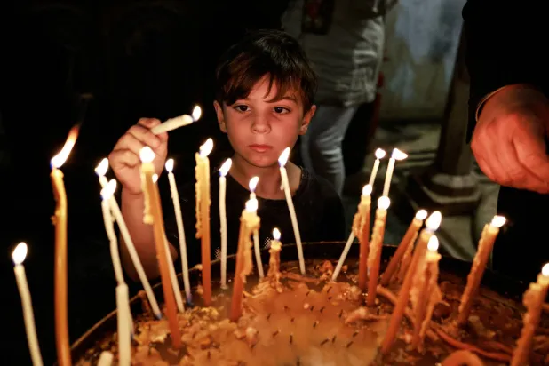 ذرف بعض الحضور الدموع خلال الصلوات التي دوت أصداؤها في القاعة المستديرة بالكنيسة بينما أشعل آخرون الشموع (رويترز)