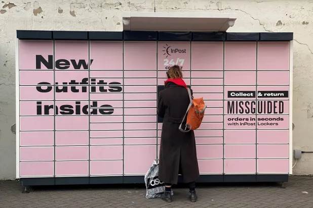 FILE PHOTO: A woman stands at an InPost locker with an ASOS package at her feet in Hackney, London, Britain, January 26, 2021. REUTERS/Simon Newman/File Photo
