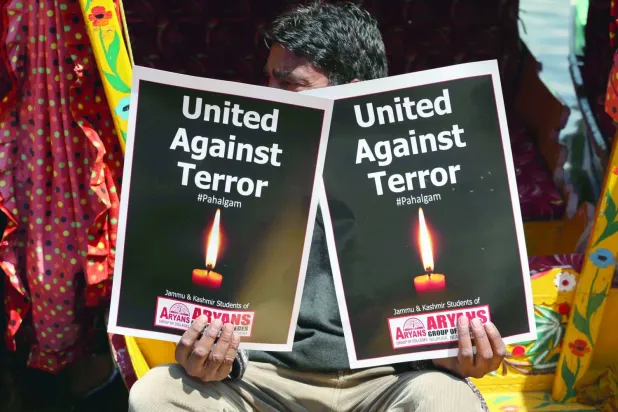 Keşmirli kayıkçı, 24 Nisan 2025'te Srinagar'da düzenlenen bir protesto sırasında Hindistan yönetimindeki Keşmir'de turistlere yönelik ölümcül saldırıyı kınayan dövizler tutuyor (EPA)