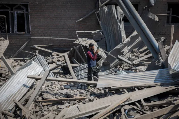 رجل يصوّر شريط فيديو لمنزل يملكه مشتبه به في هجوم باهالغام دمره الجيش الهندي بعبوة ناسفة (رويترز)