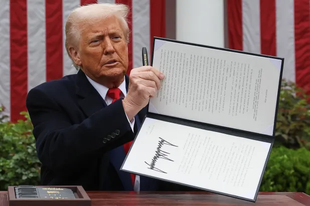 ترمب يحمل أمراً تنفيذياً موقعاً بشأن الرسوم الجمركية في حديقة البيت الأبيض (رويترز)