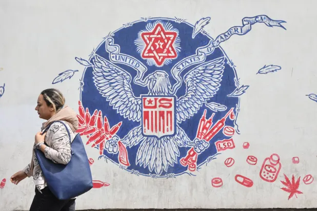 إيرانية تمر أمام رسم مناهض للولايات المتحدة على حائط سفارتها السابقة وسط طهران (رويترز)