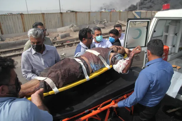 عمال إنقاذ يحملون مصاباً بعد الانفجار في رصيف ميناء رجائي (رويترز)