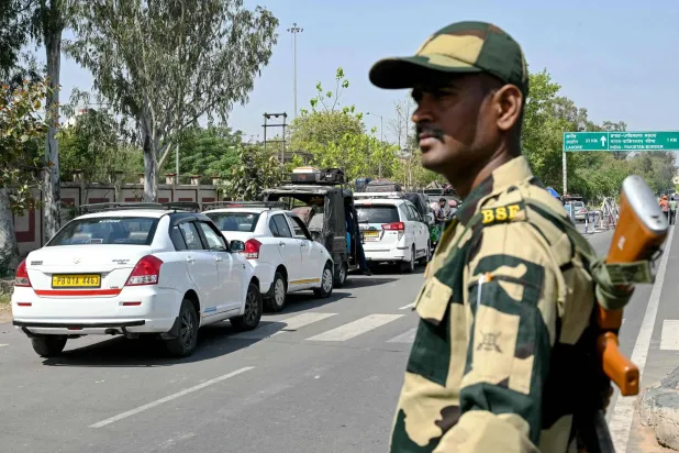 أحد جنود حرس الحدود الهندي يقف متأهباً بينما يعود باكستانيون إلى بلادهم عبر معبر حدودي (أ.ف.ب)