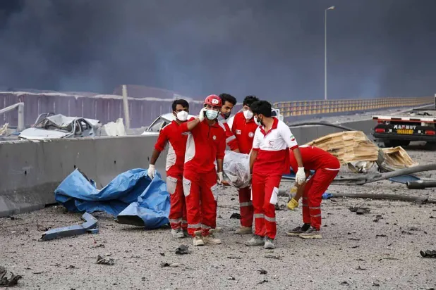 «الصليب الأحمر» الإيراني ينقل ضحية من موقع انفجار ميناء رجائي (أ.ف.ب)