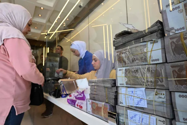 امرأة سورية تتحدث مع موظفة في محل صرافة بدمشق (أ.ف.ب)