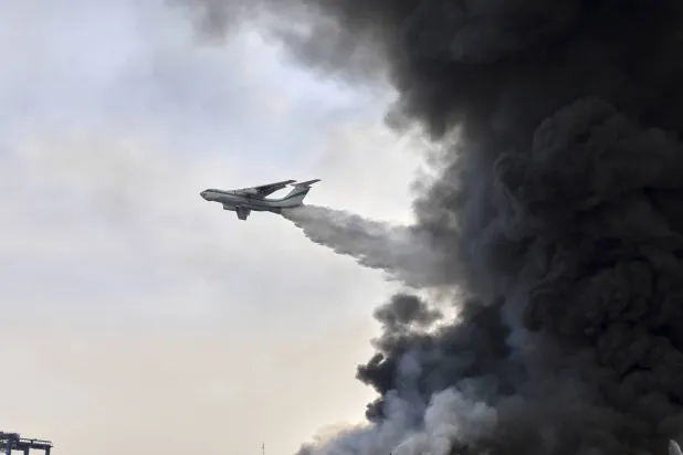 طائرة إطفاء تابعة لـ«الحرس الثوري» ترش الماء على حريق ميناء رجائي في بندر عباس جنوب إيران (أ.ب)