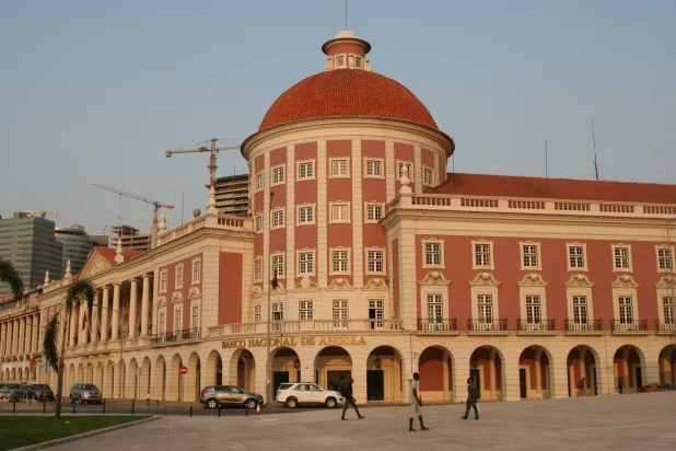 مواطنون يسيرون بجانب مبنى البنك المركزي في العاصمة الأنغولية لواندا (رويترز)