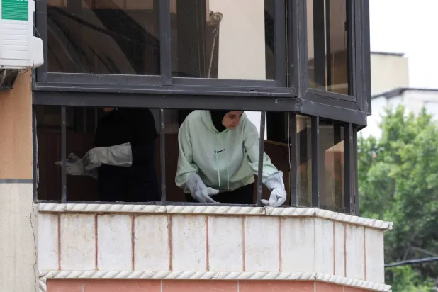 سيدة تزيل الركام في أحد المنازل المتضررة نتيجة الغارة الإسرائيلية على الضاحية الجنوبية يوم الأحد (رويترز)