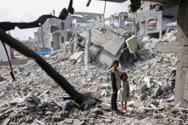 فتاتان فلسطينيتان تنظران إلى أنقاض مبانٍ دمرتها غارات إسرائيلية في بيت لاهيا شمال غزة (أ.ف.ب)