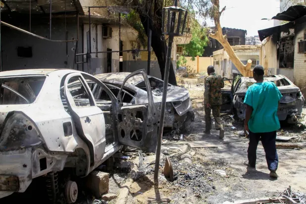 Hartum'da tahrip edilmiş araçların yanından geçen insanlar, 28 Nisan 2025 (AFP)