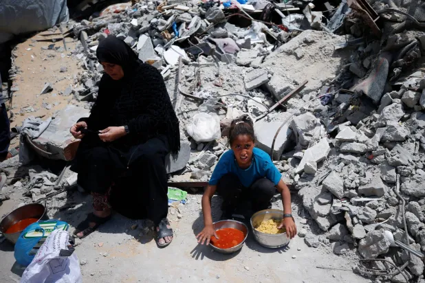 امرأة وفتاة فلسطينيتان تحصلان على حصص طعام في بيت لاهيا بشمال قطاع غزة أمس (رويترز)