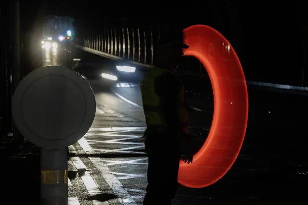 رجل شرطة يُعطي توجيهات للمركبات بعد انقطاع التيار الكهربائي في مالقا الإسبانية أمس (إ.ب.أ)