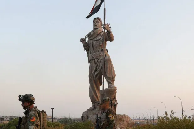 قوات الأمن العراقية تقف حراسة بالقرب من تمثال البيشمركة في كركوك (أرشيفية - رويترز)