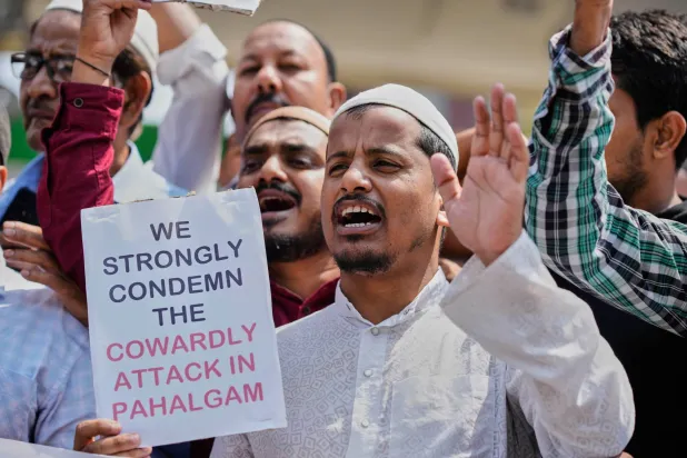 مسلم يحمل لافتة للتنديد بهجوم كشمير (أ.ب)