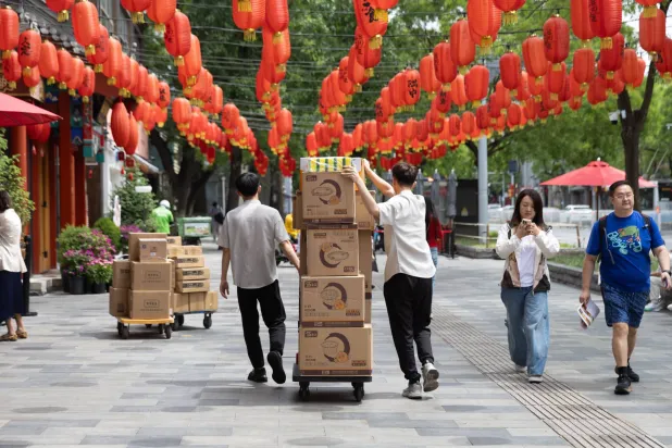 عمال ينقلون صناديق في منطقة تجارية بالعاصمة الصينية بكين (إ.ب.أ)