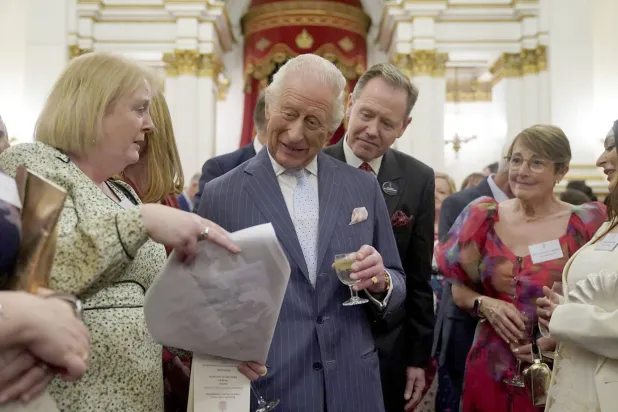 الملك تشارلز يتحدث إلى الضيوف خلال حفل استقبال بقصر باكنغهام في لندن احتفالاً بالمبادرات المجتمعية التي تهدف إلى زيادة الوعي بالسرطان (أ.ب) 