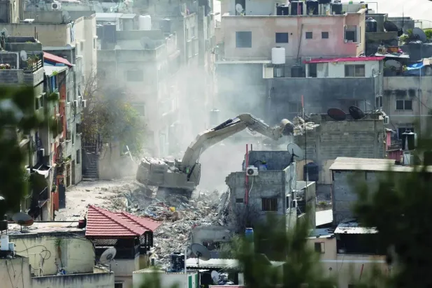 Bir İsrail buldozeri, 6 Mart 2025 tarihinde Batı Şeria'nın Tulkerim kenti yakınlarındaki bir askeri operasyon sırasında binaları yıkıyor. (EPA)