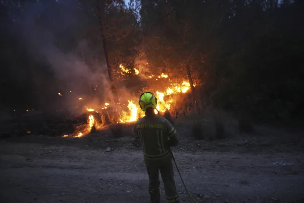 رجل إطفاء إسرائيلي يعمل على إخماد حريق غابات بالقرب من القدس (أ.ب)