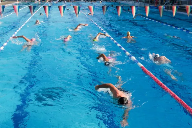 أشخاص يسبحون في مسبح خارجي مع ارتفاع درجات الحرارة بشرق لندن 1 مايو 2025 (رويترز)