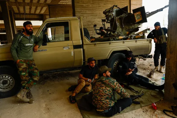 عناصر من قوات الأمن السورية يرتاحون بجوار عربتهم في بلدة صحنايا الخميس (رويترز)