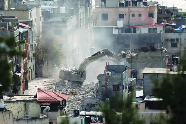 جرافة إسرائيلية تهدم مباني خلال عملية عسكرية قرب مدينة طولكرم بالضفة الغربية 6 مارس (آذار) 2025 (إ.ب.أ)