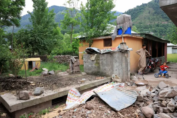 Keşmir'in Pakistan yönetimindeki bölgesinde ailesinin güvenliği için inşa ettiği sığınağın yanında duran bir adam (Reuters)