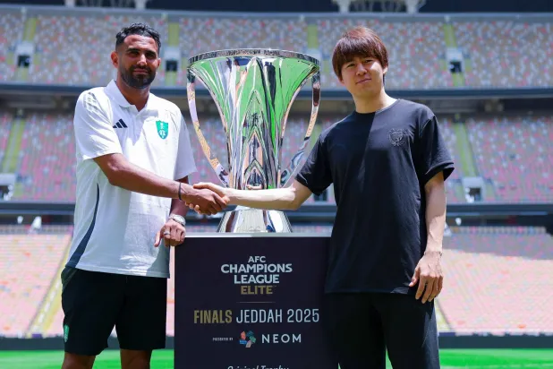 محرز وواكيزاكا يتصافحان وبينهما كأس البطولة (النادي الأهلي)