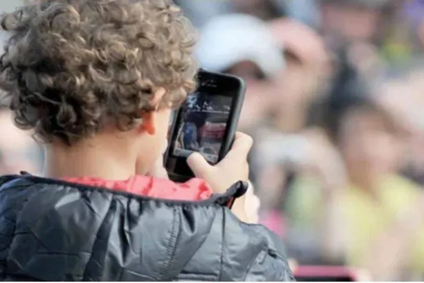 صورة ملتقطة في 20 أبريل 2013 تُظهر طفلاً يستخدم هاتفاً ذكياً في مضمار سباق كولفيلد في ملبورن (أرشيفية - أ.ف.ب)