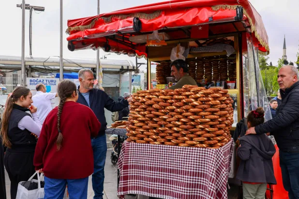 يشتري الناس «السميت» وهو خبز تركي تقليدي أثناء عرضه في كشك للبيع في حي بشكتاش في إسطنبول (رويترز)