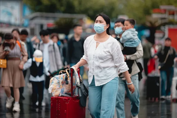 امرأة خارجة من محطة قطار بمدينة شنغهاي الصينية خلال الاحتفالات الممتدة بـ«عيد العمال»... (إ.ب.أ)