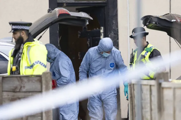 ضباط الأدلة الجنائية في الشرطة البريطانية خلال عمليات اعتقال رجل إيراني بأحد منازل بلدة روتشديل قرب مانشستر الأحد (غيتي)