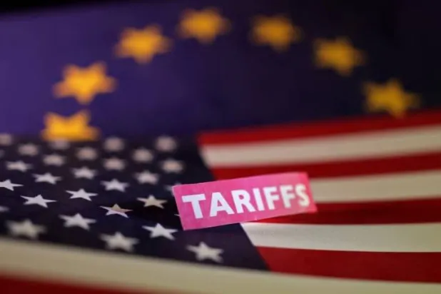 علما الولايات المتحدة والاتحاد الأوروبي إلى جانب لافتة كُتب عليها «رسوم جمركية» في هذه الصورة التوضيحية (رويترز)