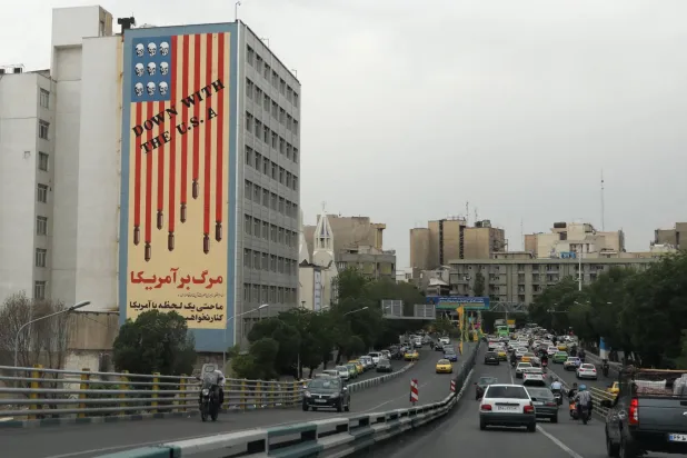 إيرانيون يمرون بجانب جدارية معادية للولايات المتحدة تحمل الشعار «الموت لأميركا» وجماجم تحل محل النجوم على العلم في طهران (أ.ف.ب)