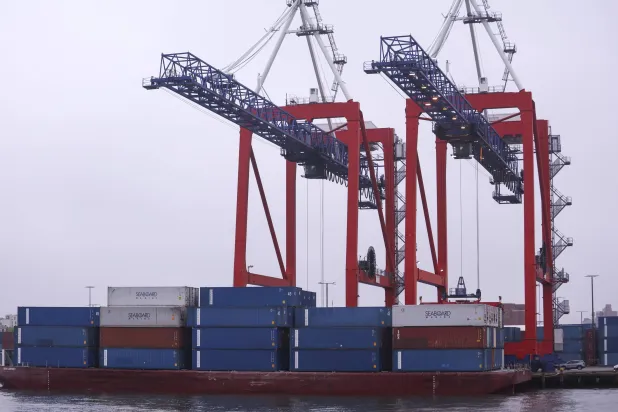 حاويات شحن تُفرَّغ من سفينة بمحطة ريد هوك البحرية في بروكلين (إ.ب.أ)