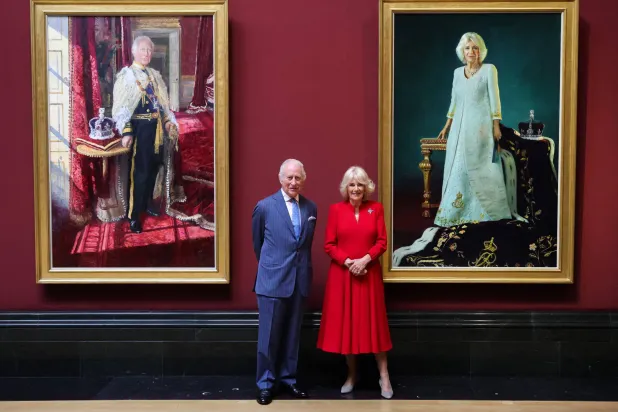 تشارلز وكاميلا أمام لوحتيهما (أ.ف.ب)