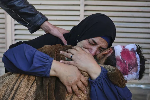 الفلسطينية مها العيان تحمل جثمان ابنها قاسم وعمره 7 سنوات بعد مقتله في ضربة إسرائيلية على مدرسة تضم نازحين بدير البلح (أ.ب)