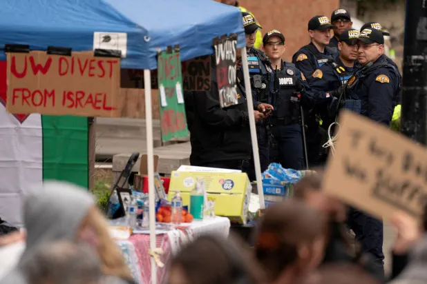 عناصر شرطة يراقبون المتظاهرين في جامعة واشنطن وهم يتجمعون للاحتجاج دعماً لقضايا تشمل الفلسطينيين والهجرة (رويترز)