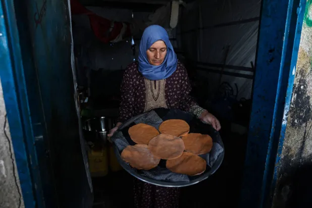 فلسطينية تحمل خبزاً مسطحاً مصنوعاً من العدس المطحون خلال أزمة نقص الدقيق في مأواها بمخيم جباليا للاجئين شمال قطاع غزة (أ.ف.ب)
