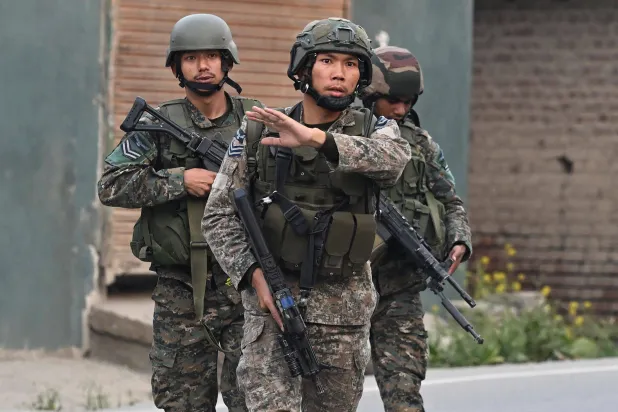 جنود هنود يسيرون على طول شارع بالقرب من سريناغار المدينة الرئيسية في الشطر الهندي من كشمير بعد سماع دوي انفجار قوي (أ.ف.ب)