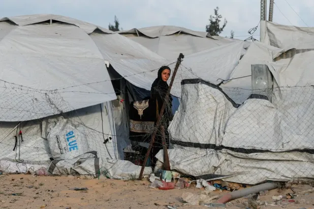 فلسطينية خلال وقوفها في وقت سابق بين خيام النازحين بخان يونس (رويترز)