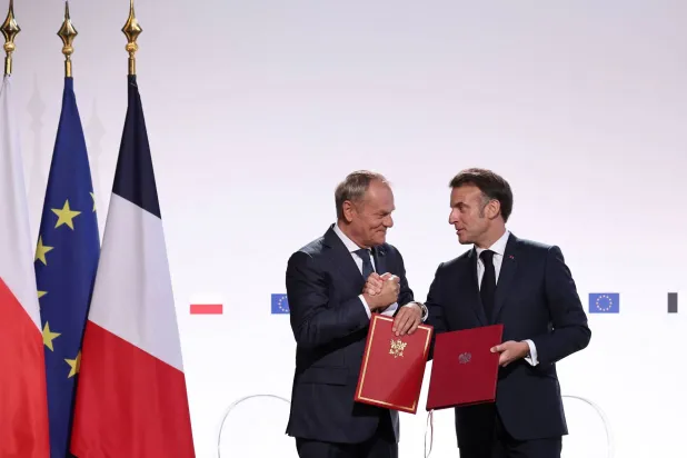 ماكرون يتبادل مع ضيفه تاسك وثيقتي المعاهدة الجديدة التي وقّعاها في مدينة نانسي الجمعة (أ.ف.ب)