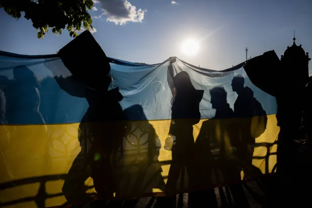أشخاص يحملون علماً كبيراً لأوكرانيا (إ.ب.أ)