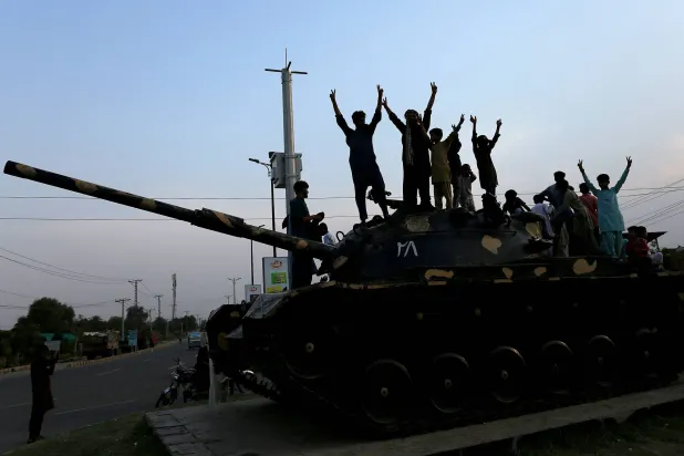 باكستانيون يحتفلون فوق دبابة بوقف إطلاق النار بين بلادهم والهند في مدينة ملتان (أ.ف.ب)